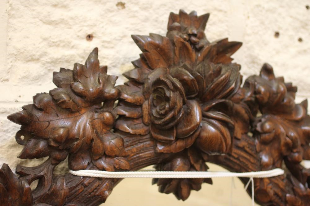 A CARVED OAK PIER GLASS, c.1900, the oval plate within a boldly carved frame with flowers and Image