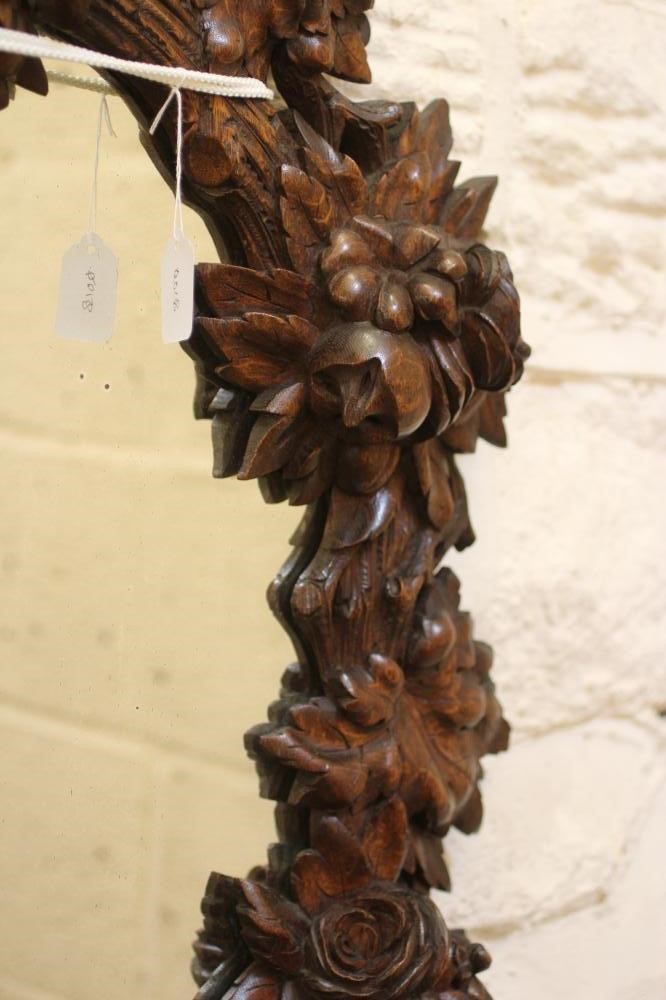 A CARVED OAK PIER GLASS, c.1900, the oval plate within a boldly carved frame with flowers and Image