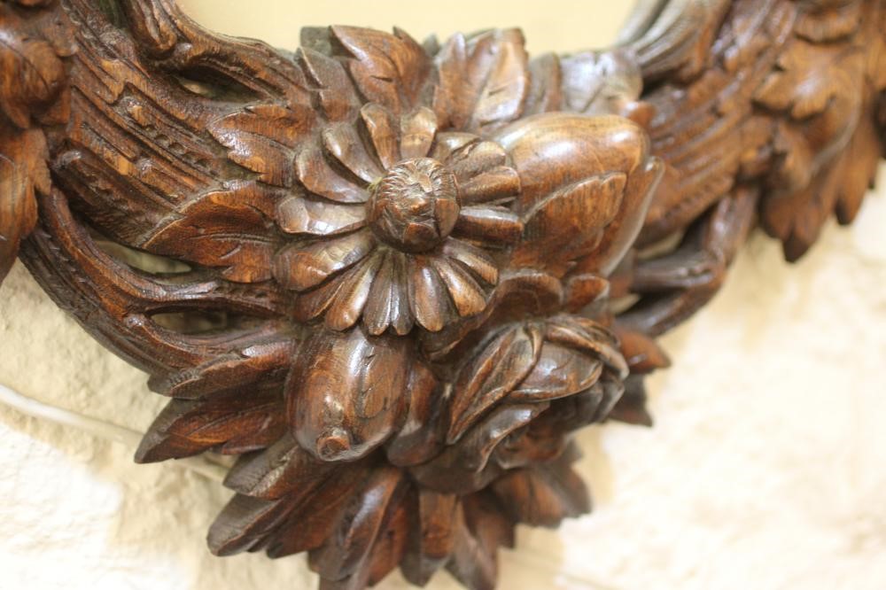 A CARVED OAK PIER GLASS, c.1900, the oval plate within a boldly carved frame with flowers and Image