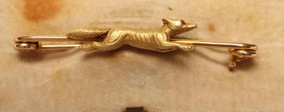 A NOVELTY STOCK BROOCH centred by a fox in flight with a ruby cabochon eye Image