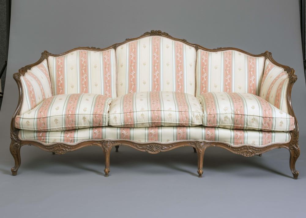 A LOUIS XVI STYLE WALNUT FRAMED SOFA of serpentine outline carved with flowers and scroll work and Image