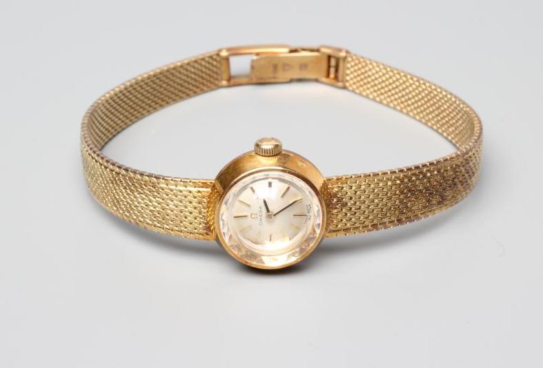 A LADY'S 14CT GOLD OMEGA WRISTWATCH, the silvered dial with gilt metal batons in a plain tapering Image