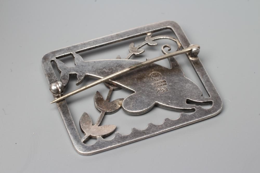 A GEORG JENSEN SILVER OBLONG BROOCH designed by Arno Malinowski cast as two dolphins swimming amidst Image