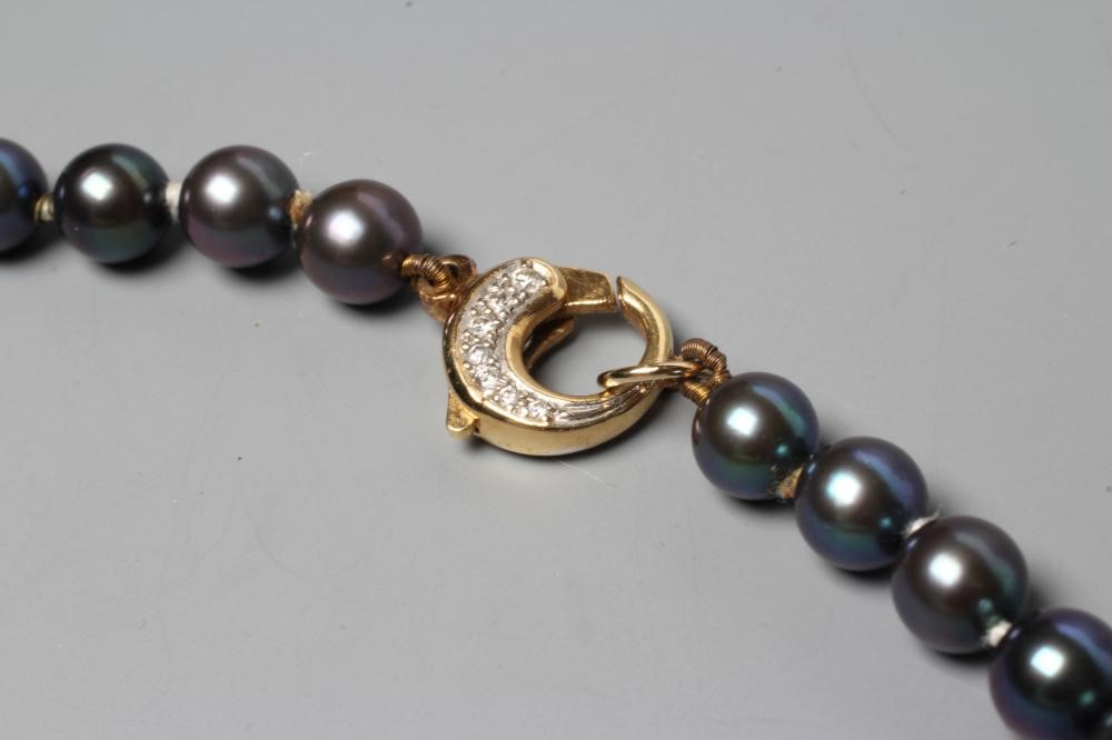 A SINGLE STRING OF BLACK CULTURED PEARLS, the circular clasp stamped 750 and point set with seven Image