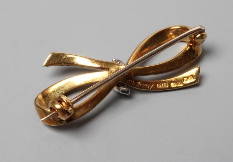 AN 18CT GOLD BOW BROOCH with hatched engraving and centred by three small brilliant cut diamonds, Image
