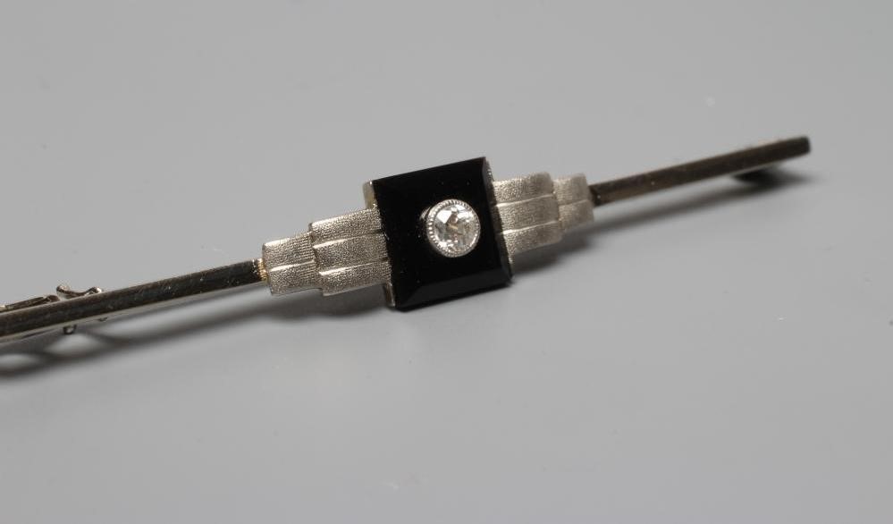 AN ART DECO BAR BROOCH, the central black onyx square panel collet set with a small diamond between Image