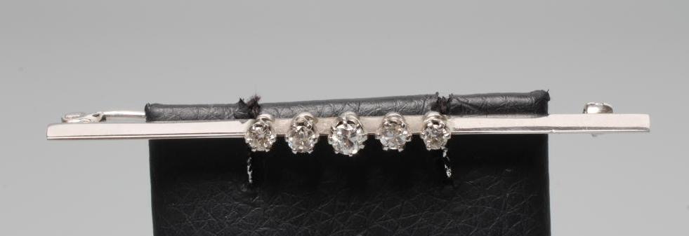 A DIAMOND BAR BROOCH, the five brilliant cut stones claw set to an unmarked plain white knife edge Image