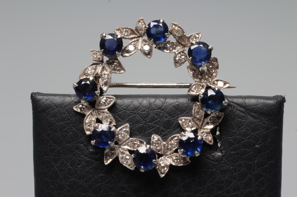 A SAPPHIRE AND DIAMOND WREATH BROOCH set with eight round cut sapphires and numerous small diamonds Image