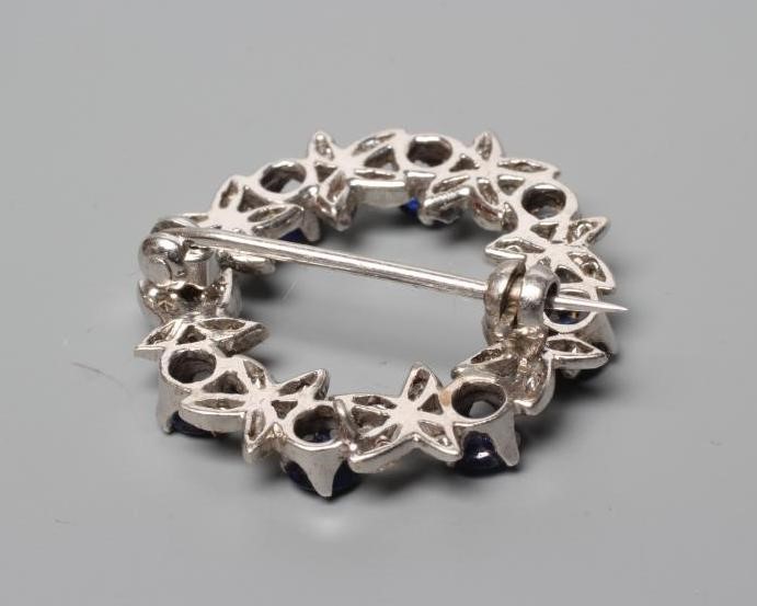 A SAPPHIRE AND DIAMOND WREATH BROOCH set with eight round cut sapphires and numerous small diamonds Image