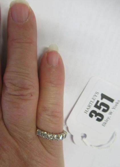 A SEVEN STONE DIAMOND HALF HOOP ETERNITY RING, the round brilliant cut stones line set to a plain Image