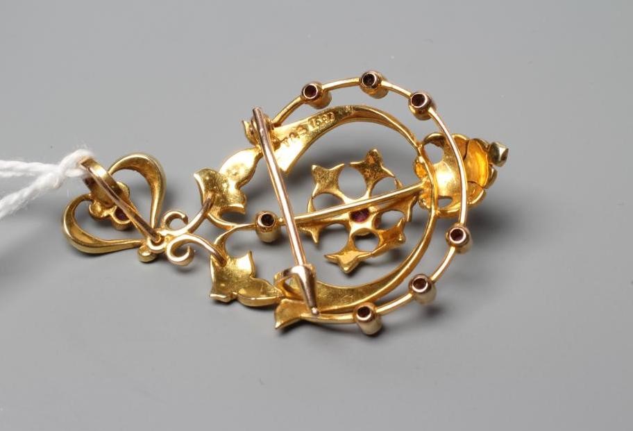AN EDWARDIAN RUBY AND SEED PEARL PENDANT/BROOCH of shaped open oval form centred by a flowerhead and Image