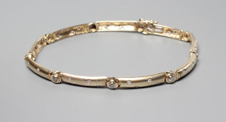 A DIAMOND BRACELET, the nine matt solid rounded oblong links each gypsy set with four small stones Image