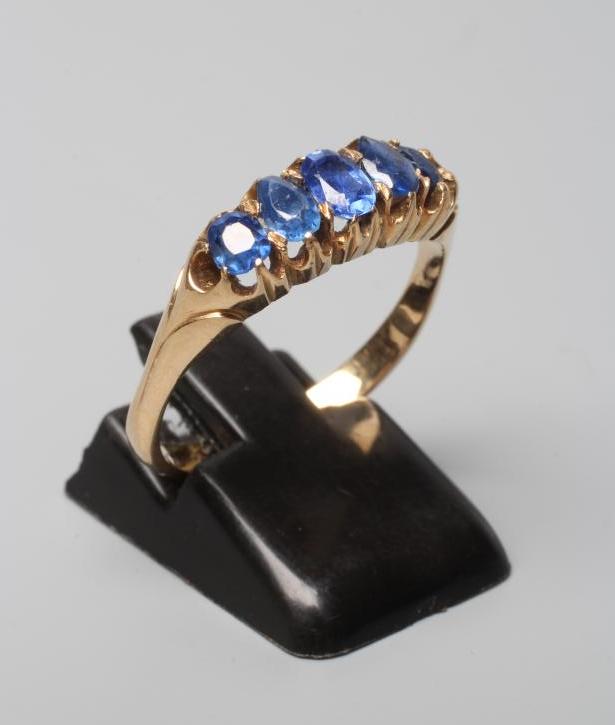 A VICTORIAN FIVE STONE SAPPHIRE HALF HOOP RING, the oval facet cut stones claw set to a plain shank Image