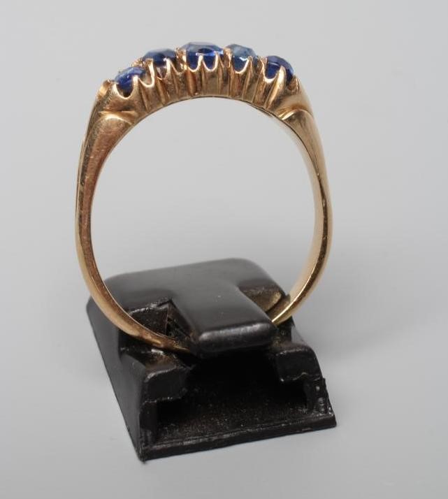 A VICTORIAN FIVE STONE SAPPHIRE HALF HOOP RING, the oval facet cut stones claw set to a plain shank Image