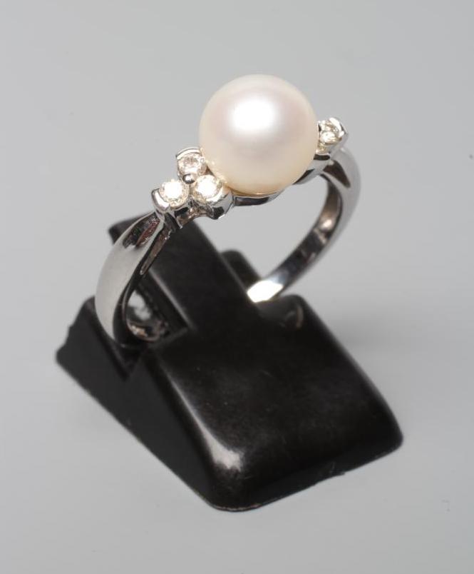 A PEARL AND DIAMOND DRESS RING, the peg set cultured pearl flanked by small brilliant cut diamonds Image