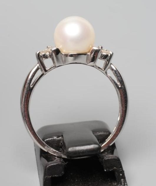 A PEARL AND DIAMOND DRESS RING, the peg set cultured pearl flanked by small brilliant cut diamonds Image