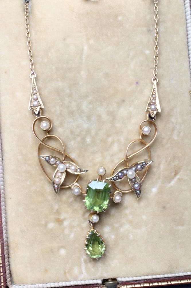 AN EDWARDIAN PERIDOT AND SEED PEARL PENDANT of typical scroll wirework form claw set with two Image