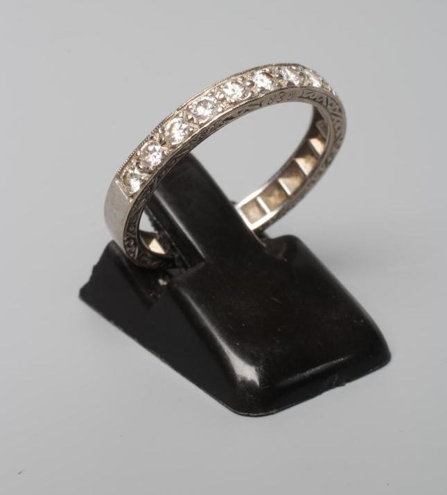 AN ELEVEN STONE DIAMOND HALF HOOP RING, the old cut stones point set to a white shank with scroll Image