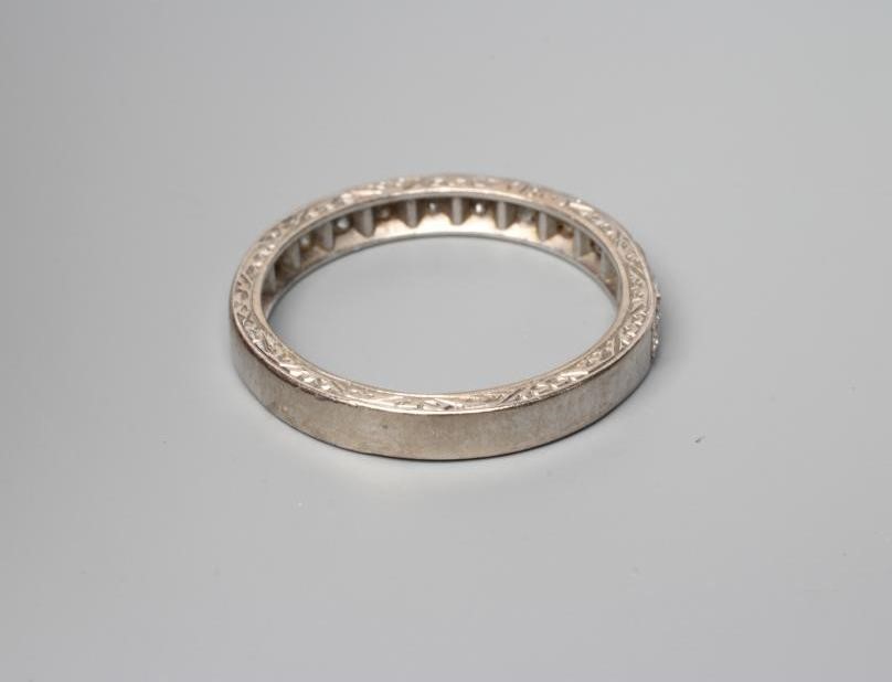 AN ELEVEN STONE DIAMOND HALF HOOP RING, the old cut stones point set to a white shank with scroll Image