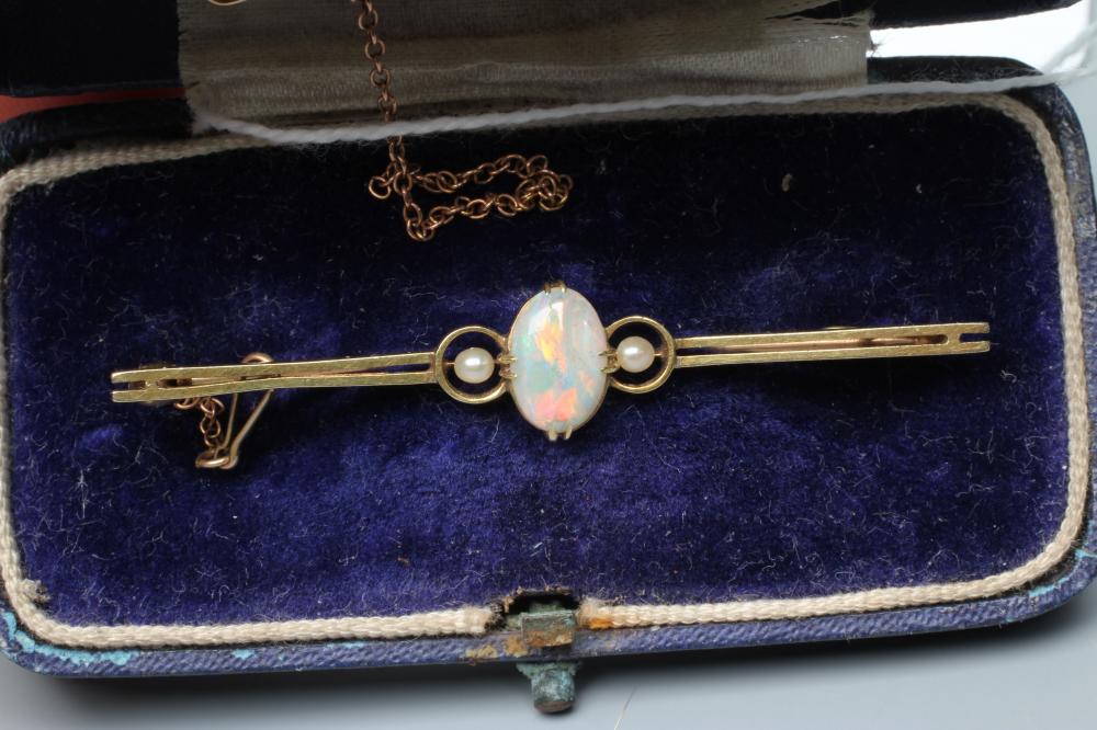 AN EDWARDIAN OPAL AND SEED PEARL BAR BROOCH, the claw set oval cabochon polished opal flanked by two Image