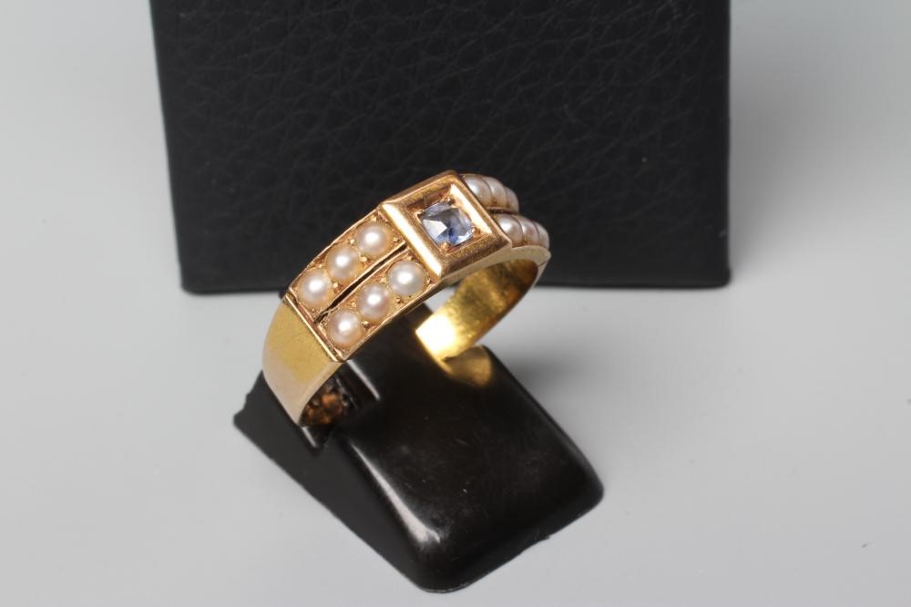 A VICTORIAN 15CT GOLD MOURNING RING centred by a point set sapphire(?) flanked by pairs of seed Image