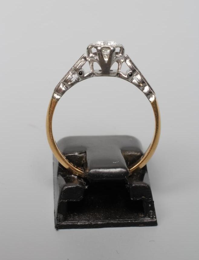 A SOLITAIRE DIAMOND RING, the old cut stone illusion set to white shoulders and a plain shank Image