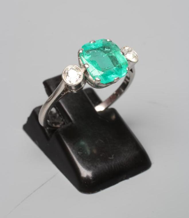 AN EMERALD AND DIAMOND THREE STONE RING Image