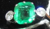 AN EMERALD AND DIAMOND THREE STONE RING Image