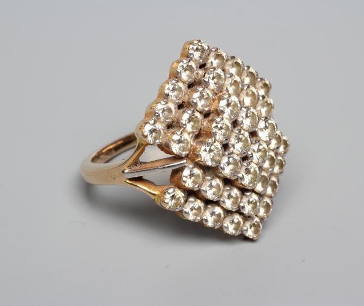 A MODERN GEOMETRIC PANEL DIAMOND CLUSTER RING, the lozenge panels claw set to a plain unmarked Image