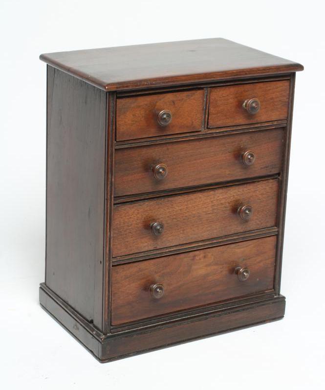 A MAHOGANY MINIATURE CHEST, early/mid 19th century, of two short over three long drawers with turned Image