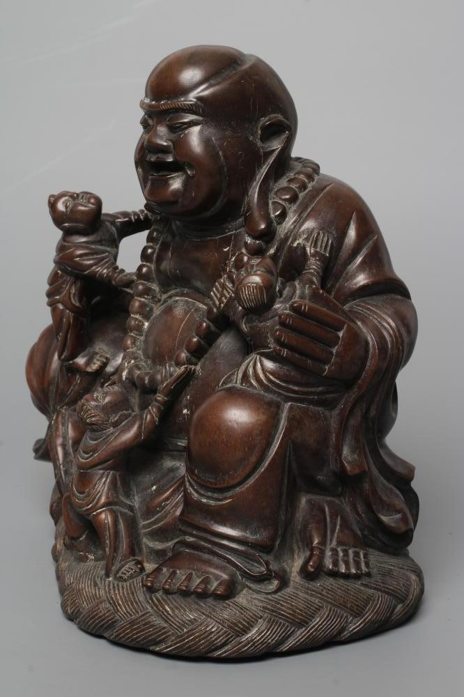 A CHINESE CARVED HARDWOOD BUDDAH, seated wearing a long bead necklace and with three children in Image