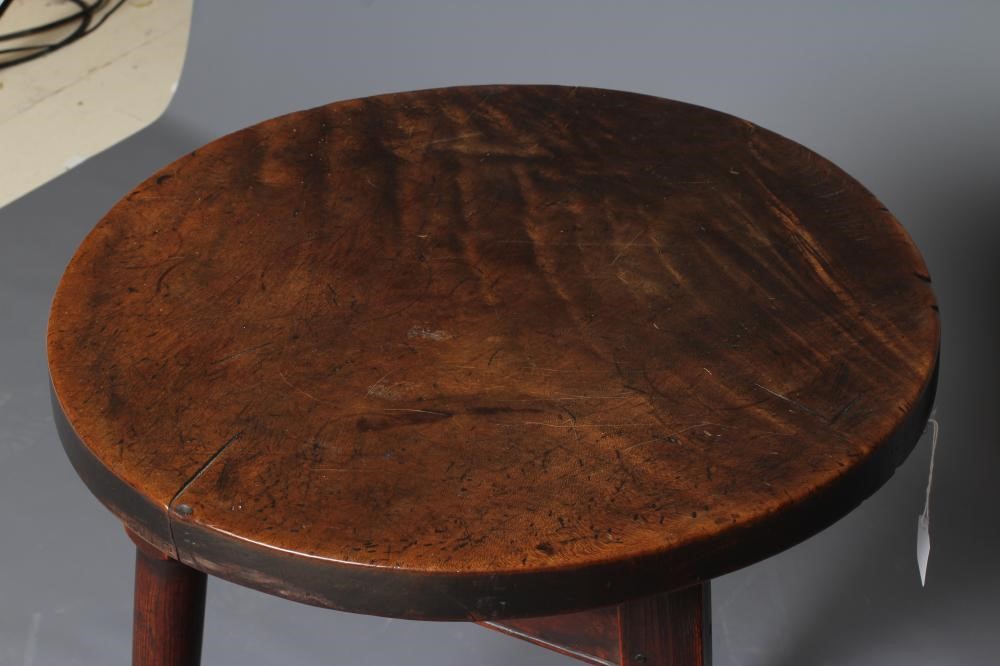 AN OAK AND FRUITWOOD(?) CRICKET TABLE, 19th century, the heavy circular top on turned tapering legs Image