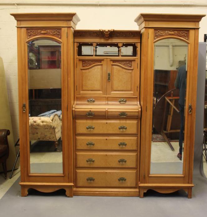 A VICTORIAN STRIPPED WALNUT TRIPLE WARDROBE comprising a pair of hanging compartments each with Image