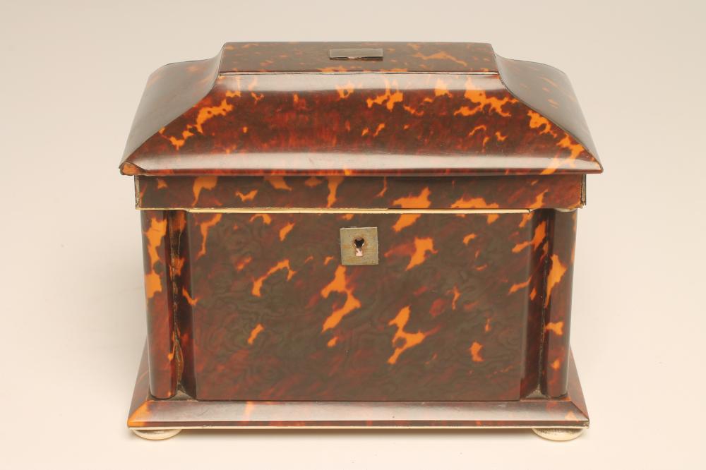 A REGENCY TORTOISESHELL TEA CADDY of panelled sarcophagus form with ivory edges and bun feet Image