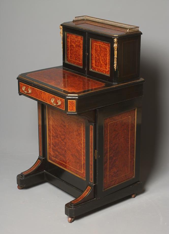 A VICTORIAN AMBOYNA AND EBONISED DAVENPORT of canted oblong form with stringing and gilt metal Image