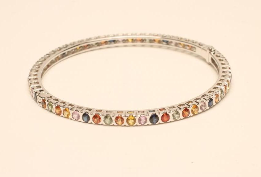 A MULTI-COLOURED SAPPHIRE STIFF HINGED BANGLE Image