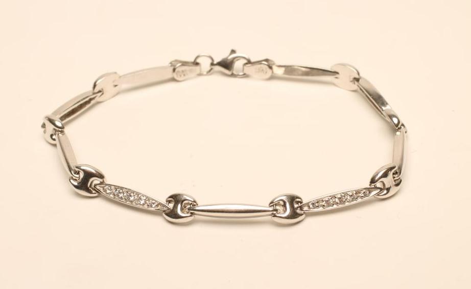 A 9CT WHITE GOLD AND DIAMOND BRACELET with four eliptical panels set with millegrain set stones and Image