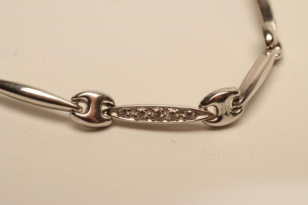A 9CT WHITE GOLD AND DIAMOND BRACELET with four eliptical panels set with millegrain set stones and Image