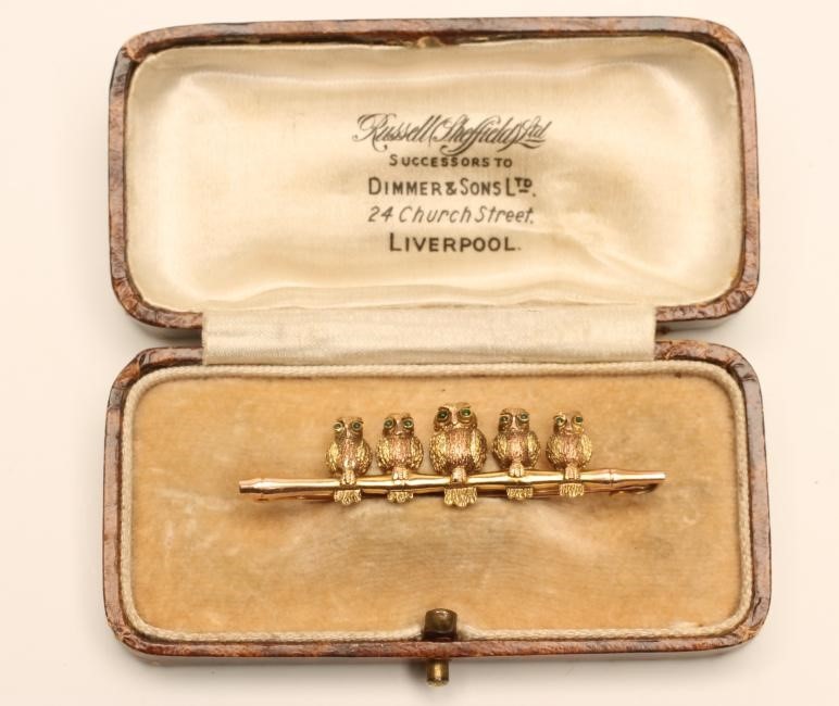 A TRI COLOUR GOLD NOVELTY BAR BROOCH modelled as five owls perched upon a naturalistically cast Image