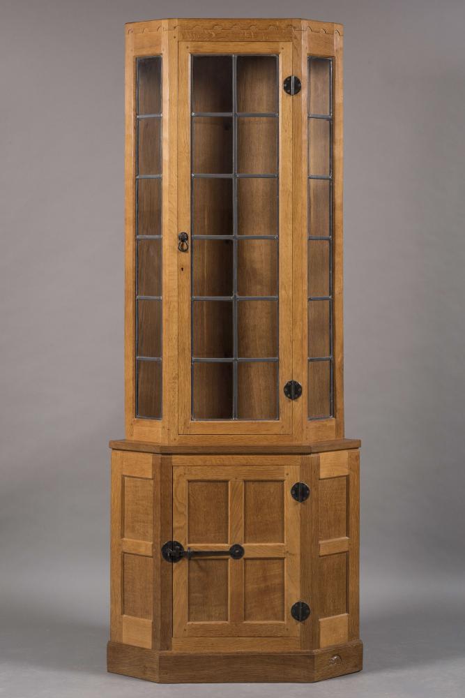 A ROBERT THOMPSON ADZED OAK STANDING CORNER CUPBOARD of canted two stage form Image