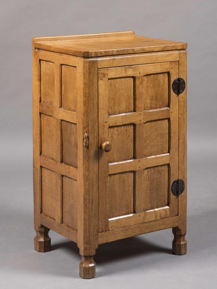 A ROBERT THOMPSON ADZED OAK BEDSIDE CUPBOARD of canted oblong multi panel form Image