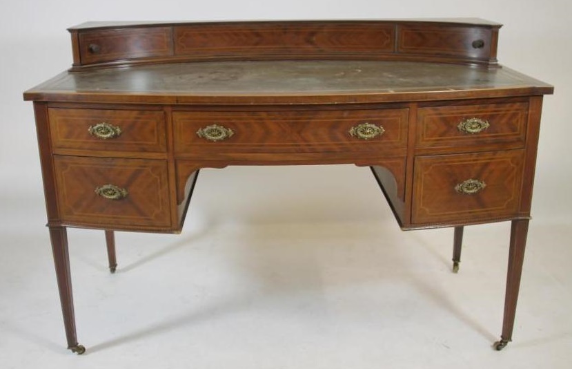 AN EDWARDIAN MAHOGANY DESK of bowed form with stringing and chequer banding Image