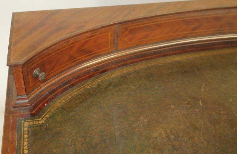 AN EDWARDIAN MAHOGANY DESK of bowed form with stringing and chequer banding Image