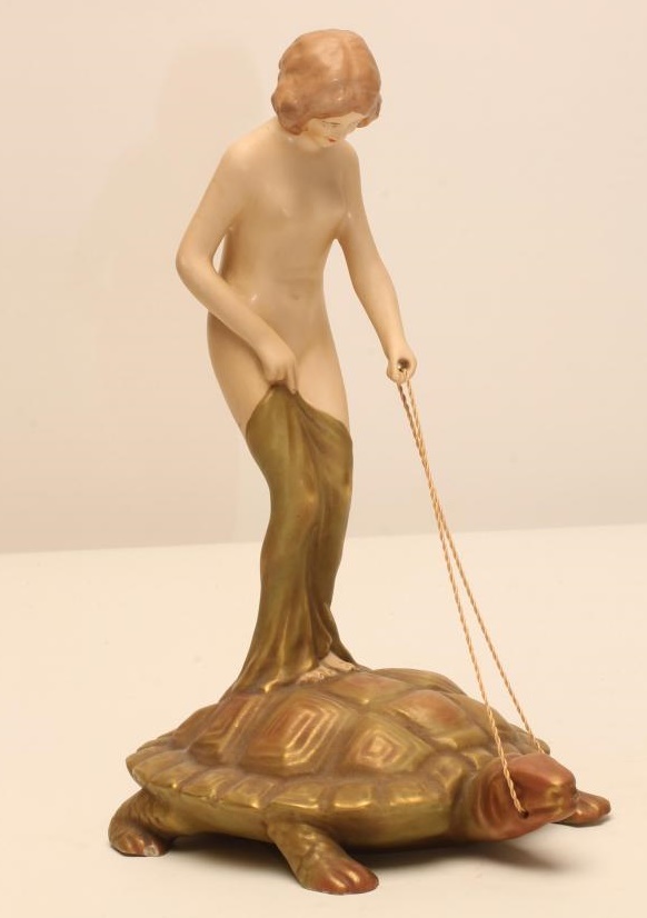 AN ART NOUVEAU ROYAL DUX BISQUE PORCELAIN FIGURE modelled as a naked maiden standing on the back of Image