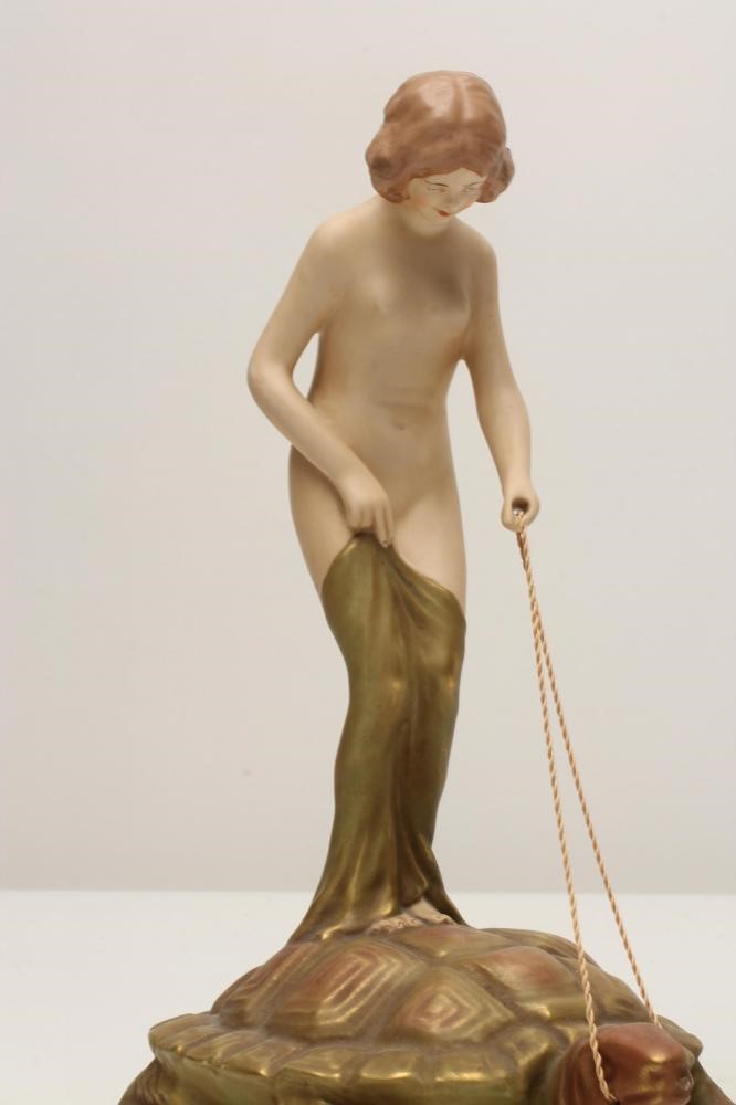 AN ART NOUVEAU ROYAL DUX BISQUE PORCELAIN FIGURE modelled as a naked maiden standing on the back of Image