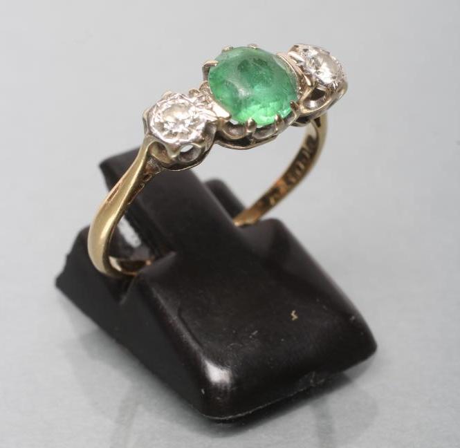 AN EMERALD AND DIAMOND THREE STONE RING Image