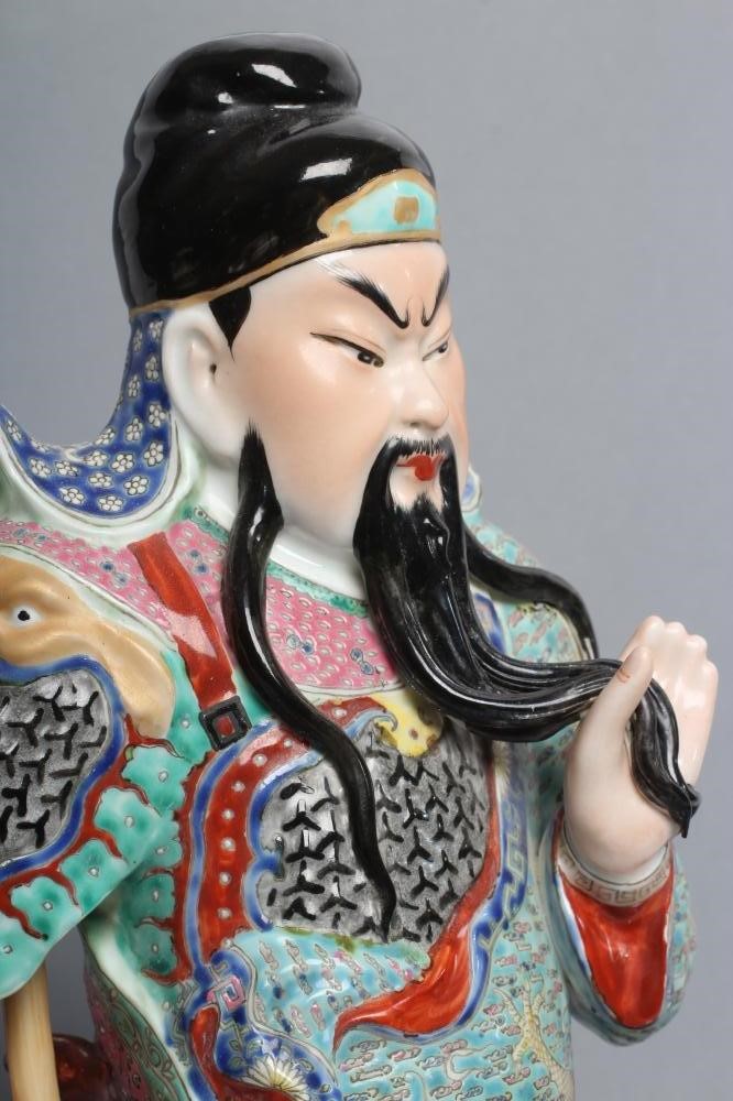 A CHINESE PORCELAIN FIGURE modelled as a celestial warrior wearing brightly coloured robes holding a Image