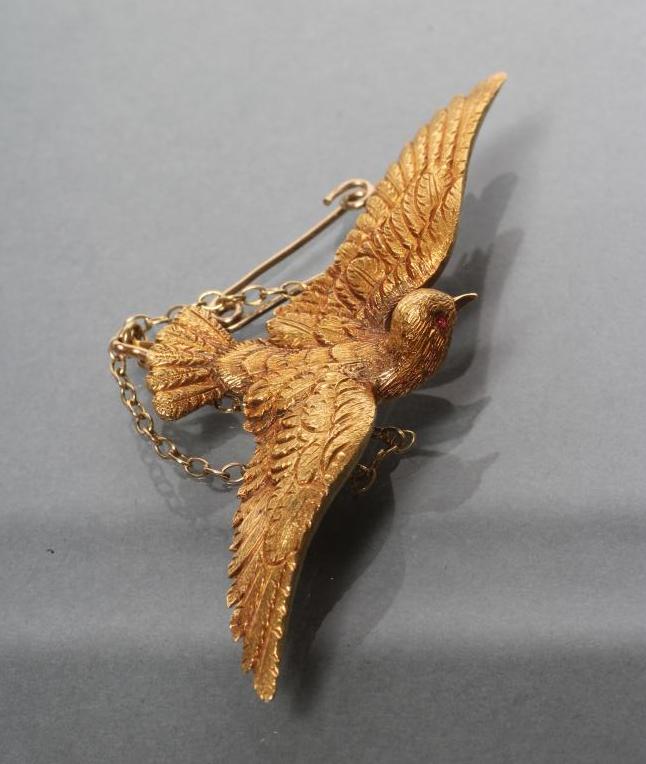 A LATE VICTORIAN DOVE IN FLIGHT BROOCH with chased feathers and ruby eyes Image