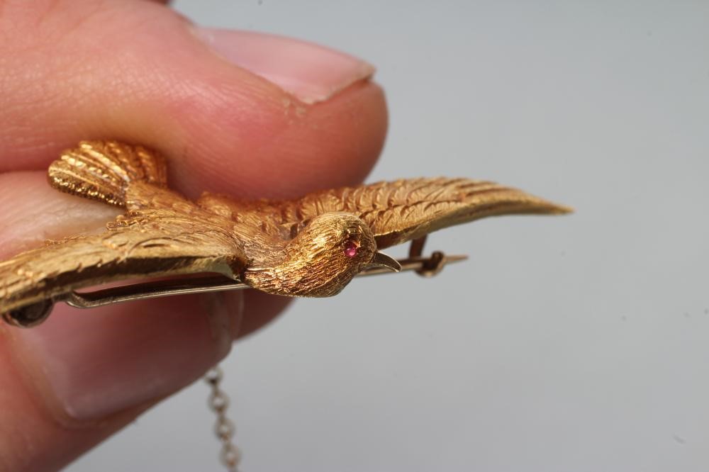 A LATE VICTORIAN DOVE IN FLIGHT BROOCH with chased feathers and ruby eyes Image