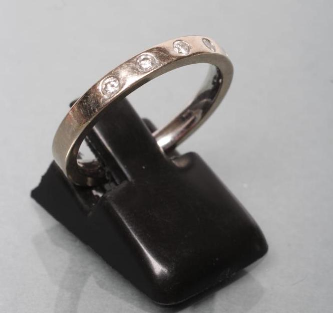 A WHITE WEDDING RING set with five small brilliant cut diamonds Image